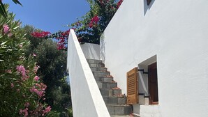 Un bâtiment blanc avec un mur en pierre et un escalier menant à une porte en bois.
