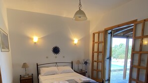 Une chambre à coucher comprenant un lit, des lampes de chevet, un ventilateur fixé au mur et un luminaire au plafond.