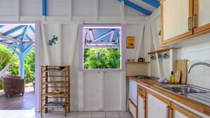 Une cuisine avec une fenêtre, des placards en bois et une étagère contenant des ustensiles de cuisine.