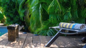Une terrasse en bois avec une chaise en métal et une serviette à rayures.
