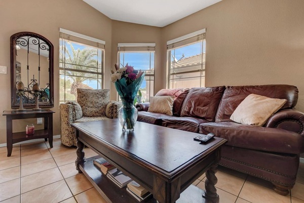 Sunny living room with leather sofa, bay windows & cozy seating