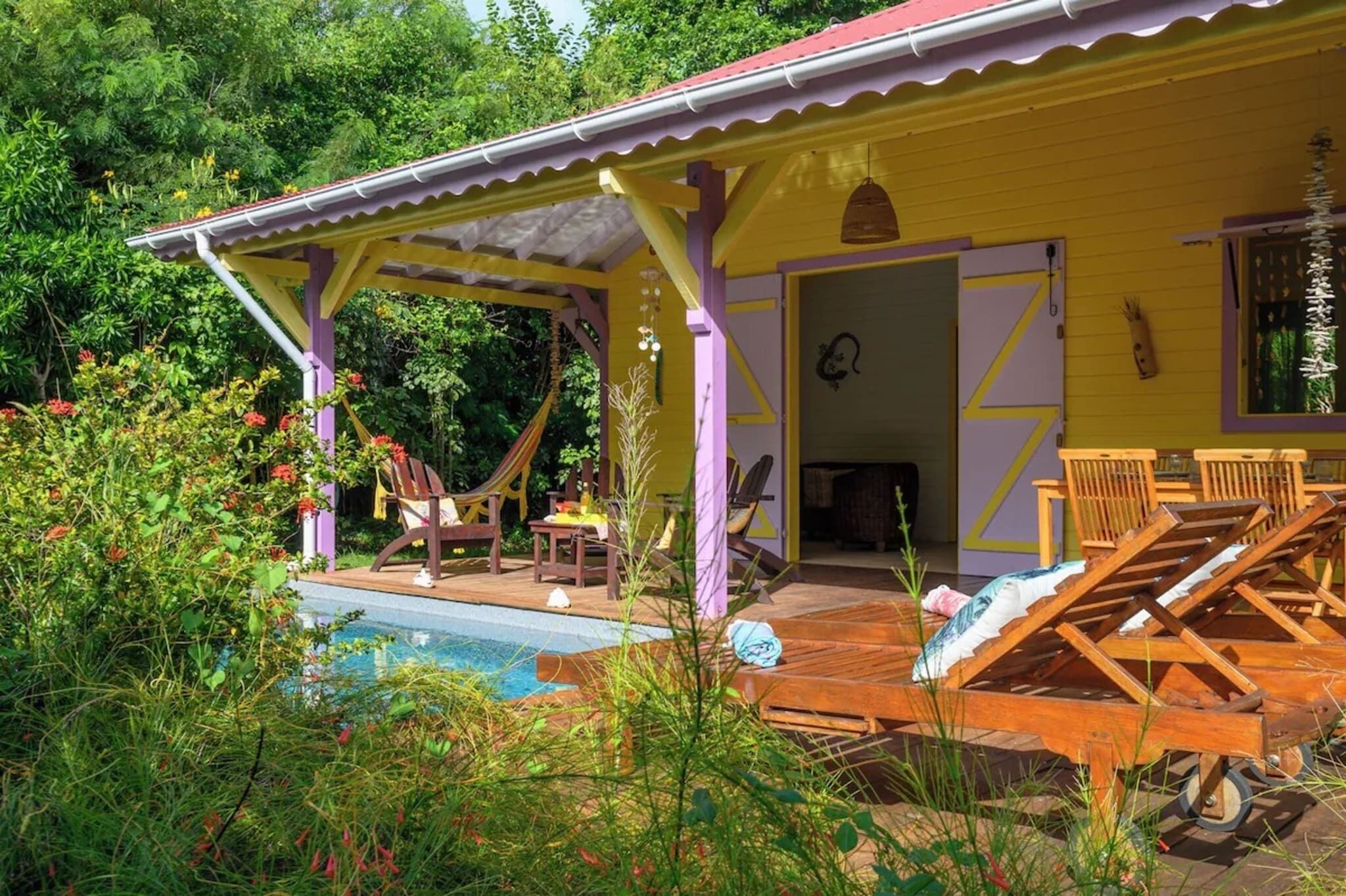 Un bâtiment jaune doté d’un patio couvert, d’une piscine et de chaises longues.