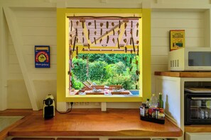 A kitchen with a window overlooking a garden, a microwave, and a coffee maker on the counter.