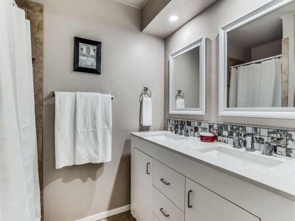 A bathroom with two sinks, a large mirror, a framed picture on the wall, and a towel rack.