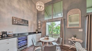 Una cocina moderna con un enfriador de vino, una mesa de comedor con sillas y un amplio ventanal con cortinas.