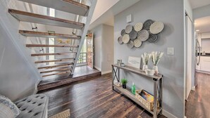Un interior moderno con una escalera de madera, una consola decorativa y una pared con diseños circulares.