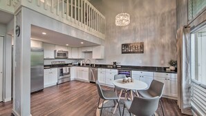 Una cocina moderna con comedor, que presenta una araña, electrodomésticos de acero inoxidable y vistas al exterior.