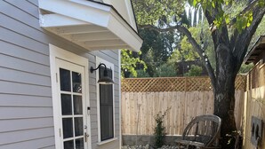 A covered patio area with a wooden deck, a bench, and a small garden with rocks and a tree. - Downtown Cozy Cottage, two blocks from downtown and new! (Paso Robles)