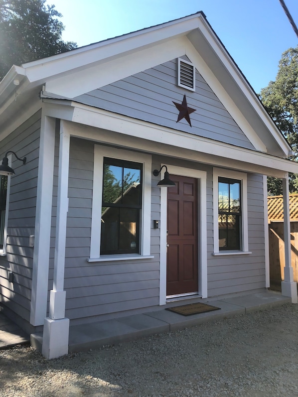 A small, single-story building with a brown door, white trim, and a star decoration above the door.