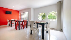 Un comedor con pared roja, sillas blancas y una mesa.