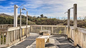 A wooden deck with a bench and a table, surrounded by a wooden fence and vegetation. - Emerald Isle Condo w/ Indoor Pool & Beach Access! (Emerald Isle)