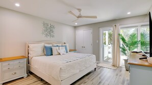 A bedroom with a bed, nightstand, ceiling fan, and a view of the outdoors. - Emerald Isle Condo w/ Indoor Pool & Beach Access! (Emerald Isle)