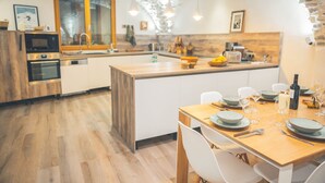 Une cuisine moderne avec des meubles en bois, un grand îlot central et un coin repas aménagé pour six personnes.