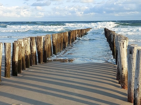 A wooden pier leading to the ocean with waves crashing against it.