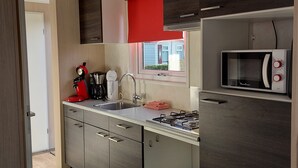 Une cuisine moderne équipée d’une cuisinière à gaz, d’un four à micro-ondes, d’une machine à café et d’un évier.
