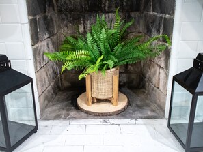 Cozy corner with a stone fireplace, lush ferns, and elegant lanterns.