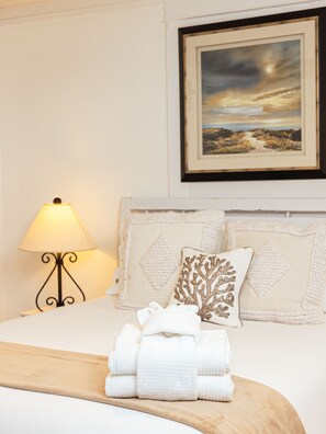 Enjoy a serene retreat with a neatly made bed, decorative pillow, and framed artwork.