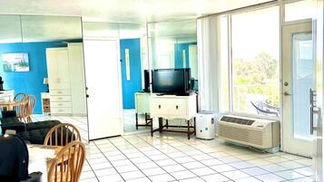Ein Wohnzimmer mit Fernseher, einem weißen Schrank und einem Fenster.