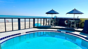 Piscina con indicador de profundidad de 1.2 metros, mobiliario exterior y vista a la playa.