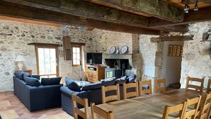 Un intérieur rustique avec un mur en pierre, des meubles en bois, une cheminée et un téléviseur.