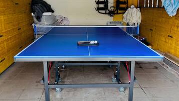 A ping pong table in a room with a tiled floor, wooden walls, and a ceiling with visible beams.