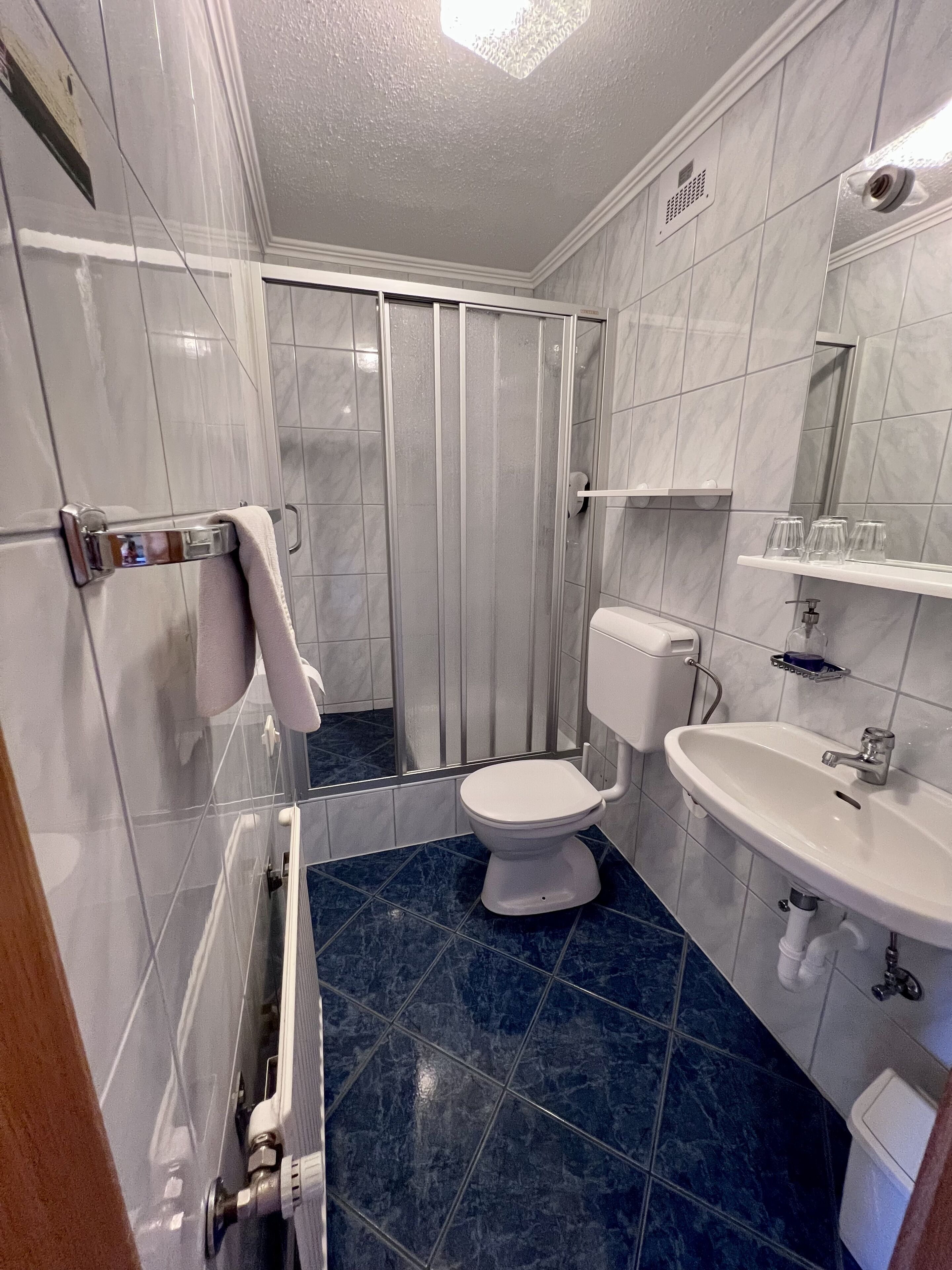 A bathroom with a shower, toilet, sink, and a mirror.