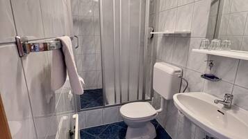 A bathroom with a shower, toilet, sink, and a mirror.
