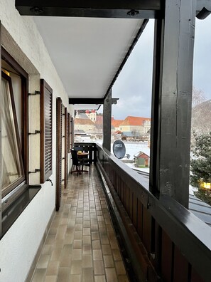 A balcony with a tiled floor, wooden railings, and a table with chairs. - Pension Lambrecht (Sankt Lambrecht)