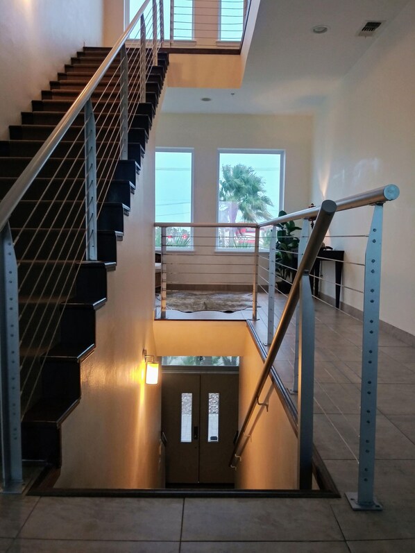 Un intérieur moderne avec un escalier, un balcon et une vue sur l’extérieur.