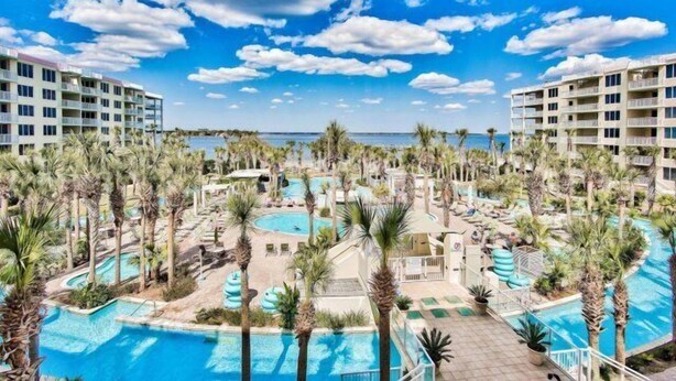 Un complexe hôtelier doté de plusieurs piscines, de palmiers et offrant une vue sur la plage.