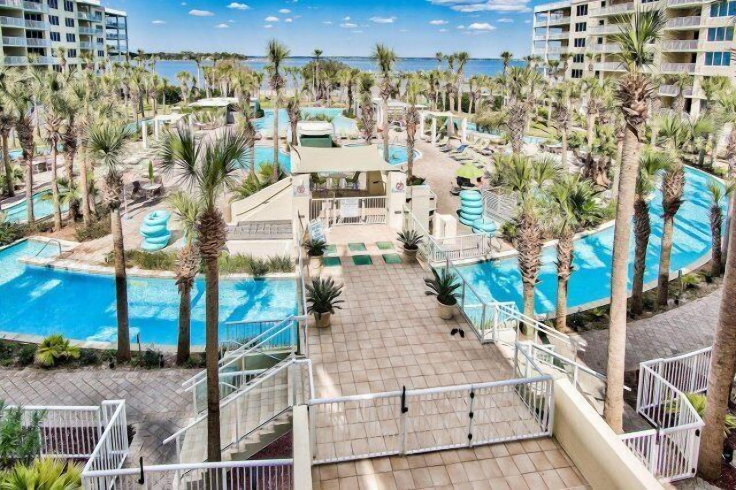 Un resort con varias piscinas, palmeras y vistas al océano.