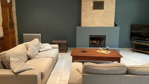 Ein Wohnzimmer mit einer Couch, einem Couchtisch, einem Kamin, einem Fernseher und einer Wanduhr.