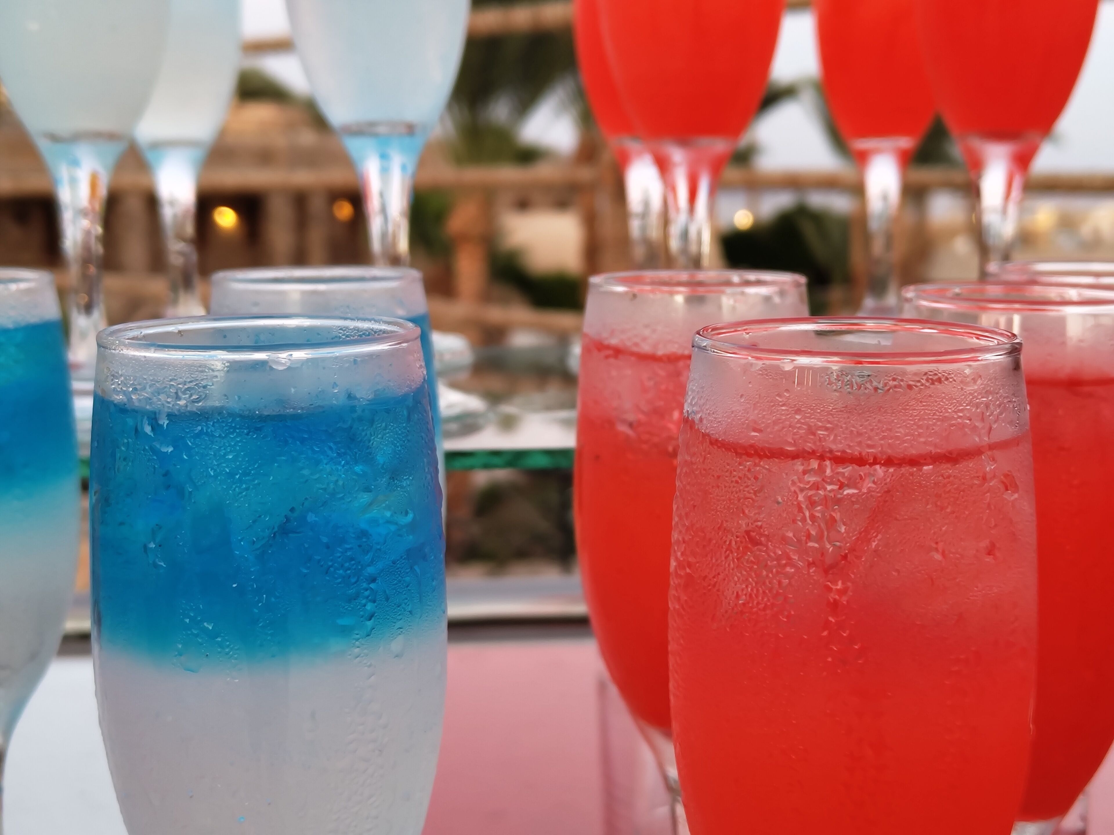 A row of glasses filled with colorful beverages, likely at a social event or gathering.