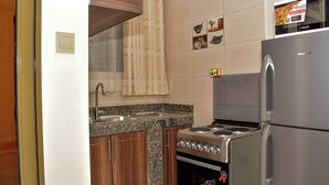 A kitchen with a stainless steel refrigerator, a built-in oven, a stovetop, and granite countertops. - Studio Furnished Apartments Entebbe (Entebbe)