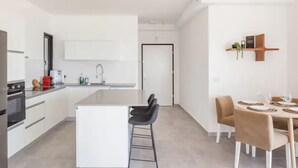 Una cocina moderna con armarios blancos, una isla central y taburetes de bar.