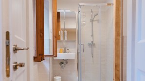 Une salle de bain moderne avec une cabine de douche en verre, un cadre de porte en bois et un tapis de bain jaune.