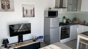 A compact kitchen with a microwave, refrigerator, stove, and sink. There is a dining area with a table and chairs. - 100% self-contained studio at the foot of the Dentelles de Montmirail (Violes)