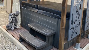 A hot tub with a wooden pergola, a decorative statue, and a sign indicating a spa area. - 100% self-contained studio at the foot of the Dentelles de Montmirail (Violes)
