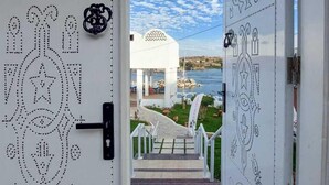 A view through a door with intricate patterns, leading to a building with a white facade and a clear sky. - NUB INN (Aswan)