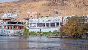 A waterfront hotel with multiple buildings, including a prominent white structure with balconies. - NUB INN (Aswan)