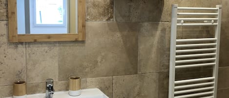 A bathroom with a white sink, wooden cup holders, a mirror, and a white towel rack.