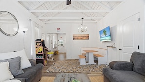 Un salon moderne avec un canapé, une table basse et un tableau représentant une scène de plage.