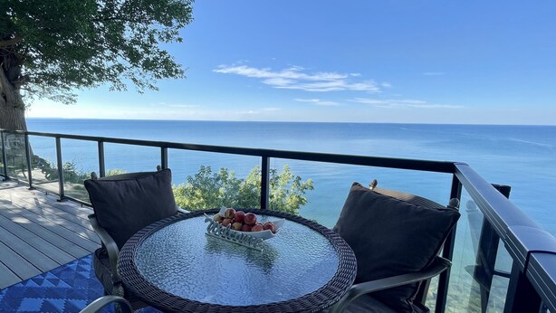 A glass table with a fruit bowl, surrounded by wicker chairs on a deck with a clear view of the sea. - COTTAGE NIAGARA DIRECT WATERFRONT  (Lincoln)