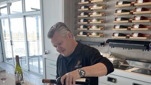 A person pouring wine into glasses on a counter with a wine rack in the background. - COTTAGE NIAGARA DIRECT WATERFRONT  (Lincoln)