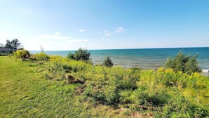 A grassy area with a view of the sea and a building in the background. - COTTAGE NIAGARA DIRECT WATERFRONT  (Lincoln)
