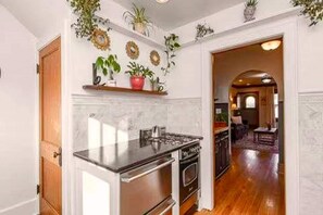 Uma cozinha com bancada de mármore, eletrodomésticos de aço inoxidável e piso de madeira.