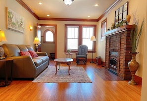 A living room with a leather sofa, a round coffee table, a fireplace, and a large window.