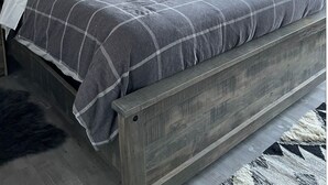 Een slaapkamer met een groot bed, een schilderij erboven en uitzicht op het buitenleven door een raam.