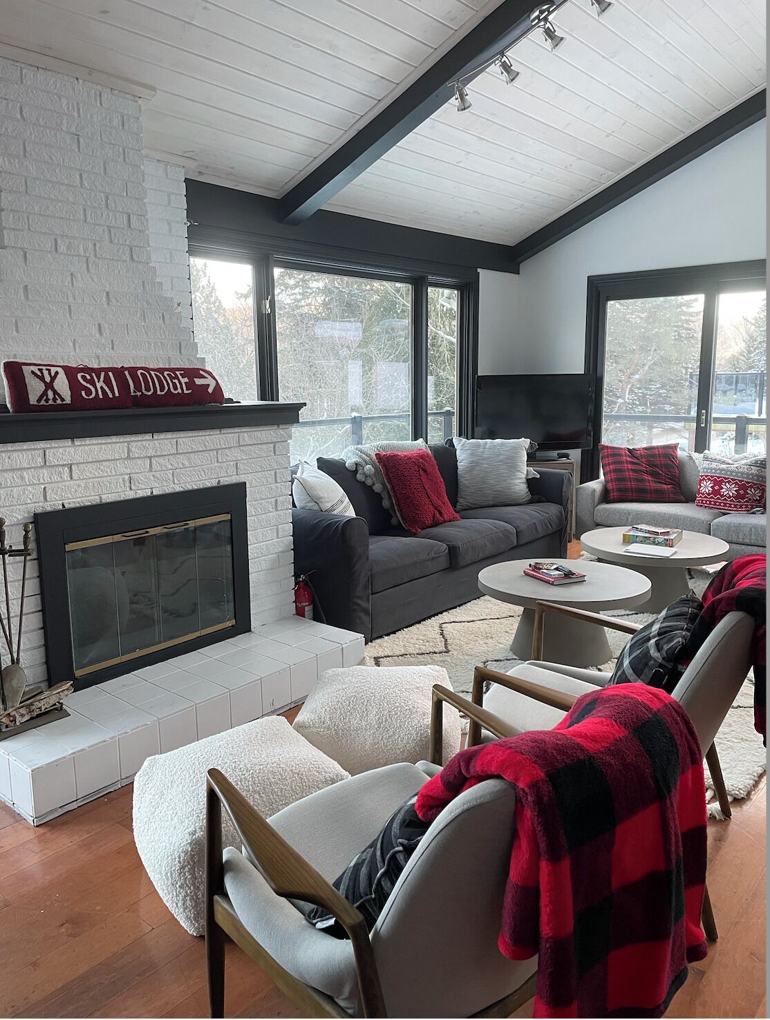 A cozy living room with a fireplace, large windows, and a ski lodge sign.