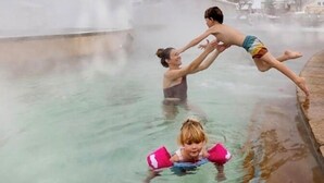 Una persona en traje de baño de pie en una piscina con vapor saliendo del agua.